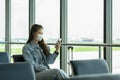 Asian young woman traveller wearing face maks using mobile phone at airport