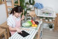 Asian young woman use finger slide on tablet screen prepare ingredients for cooking follow cooking online video clip on website in Royalty Free Stock Photo