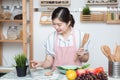 Asian young woman use finger slide on tablet screen prepare ingredients for cooking follow cooking online video clip on website in Royalty Free Stock Photo