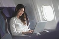 Asian young woman using laptop sitting near windows at first class on airplane