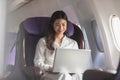 Asian young woman using laptop sitting near windows at first class on airplane during flight Royalty Free Stock Photo