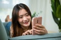 Asian young woman using smart mobile phone lying on sofa Royalty Free Stock Photo