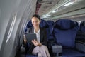 Asian young woman using tablet sitting near windows at first class on airplane during flight, Traveling and Business Royalty Free Stock Photo