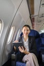 Asian young woman using tablet sitting near windows at first class on airplane during flight, Traveling and Business Royalty Free Stock Photo