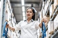 Asian young woman walks with shopping cart walking for choosing new furniture in big store warehouse