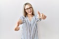 Asian young woman wearing casual clothes and glasses approving doing positive gesture with hand, thumbs up smiling and happy for Royalty Free Stock Photo