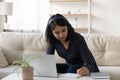 Asian young woman wearing headphones using laptop, writing notes Royalty Free Stock Photo