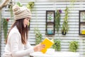 Asian young woman wearing sweater, sitting and reading book with hot coffee, smart phone at home garden in winter season. Royalty Free Stock Photo