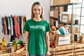 Asian young woman wearing volunteer t shirt at donations stand with a happy and cool smile on face