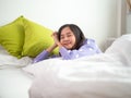 Asian young women enjoy soft bedding and mattresses in modern bedrooms. A teenage girl rests a good night sleep on holiday in bed