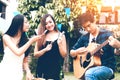 Asian young women feeding to friend with guy playing guitar sing