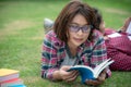 Asian young women and friends reading book on grass outside for education.