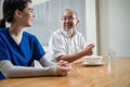 Asian young woman nurse taking care of disabled handicapped senior elderly man at nursing home. Caregiver Therapist doctor serving Royalty Free Stock Photo