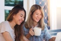 Asian young women in smart casual clothes working sending email on laptop and drinking coffee while sitting in cafe. Lifestyle