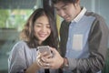 Asian younger man and woman looking to smart phone screen toothy Royalty Free Stock Photo
