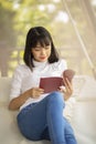 Asian younger woman ralaxing reading a book