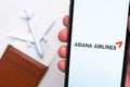 Asiana Airline app on a smartphone screen with a plane and passport on the background. The concept of travel app