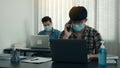 Asians sit in their office and use the phone to talk to clients while wearing masks in their offices during COVID-19