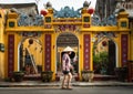 Asiatic woman walk with a tipycall vietnamese hat with a temple on background