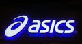 Asics logo blue neon sign. Asics is a Japanese multinational company which produces footwear and sports equipment. Royalty Free Stock Photo