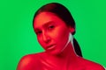 Beautiful east woman close up portrait isolated on green background in red neon light Royalty Free Stock Photo