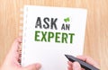 Ask an expert word on white ring binder notebook with hand holding pencil on wood table,Business concept