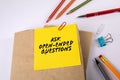 ASK OPEN-ENDED QUESTIONS. Stack of books on a white office desk