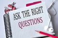 ASK THE RIGHT QUESTIONS - words in a white notebook on a white background with headphones and a pencil Royalty Free Stock Photo