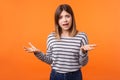 Asking why. Portrait of confused shocked woman with brown hair in long sleeve striped shirt. indoor studio shot isolated on orange