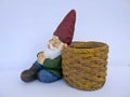 Sleeping garden gnome, sitting, leans against a basket. on white background Royalty Free Stock Photo