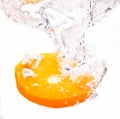 Aslice of an orange falls into a fresh glass of water and makes beautiful bubbles Royalty Free Stock Photo