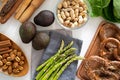 Asparagus on blue napkin, avocados, pretzel, peanuts in bowl, pecan and cinnamon sticks on wooden plate, romano salad