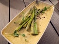 Asparagus dish on a yellow plate on a wooden table, close-up