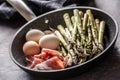 Asparagus eggs bacon and garlic in ceramic pan Royalty Free Stock Photo