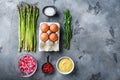 Asparagus with eggs and french dressing ingredients with dijon mustard, onion chopped in red vinegar  taragon on grey textured Royalty Free Stock Photo