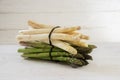 Asparagus, a green and a white bunch lie on a white painted wood