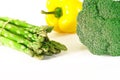 Asparagus, Juicy red and orange peppers with a green tail lies next to Bundle of lettuce and broccoli are on a white background Royalty Free Stock Photo