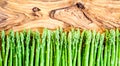 Asparagus in a row, top view on a wooden board, copy space