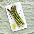 Asparagus stems on the white plate served with green lemon and cut chives Royalty Free Stock Photo