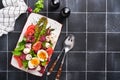 Asparagus, tomato, lettuce, mozzarella, black sesame, flax, oil olive salad and soft boiled egg on rectangular ceramic plate on Royalty Free Stock Photo