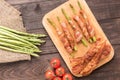 Asparagus wrapped in bacon with tomato on wooden background Royalty Free Stock Photo