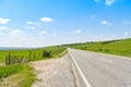 Asphalt long road crossing the green valley in a sunny summer day with bright blue sky Royalty Free Stock Photo