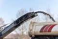 Asphalt milling and grinding machine at road repair and construction site throwing shredded old bitumen in big industrial heavy Royalty Free Stock Photo