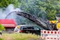 Asphalt milling and grinding machine at road repair and construction site throwing shredded old bitumen in big Royalty Free Stock Photo