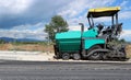 Asphalt paver vehicle on the edge of a newly paved road