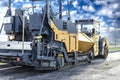 Asphalt paving equipment. Asphalt paver against the backdrop of a clear cloudy sky. Construction of new roads and road junctions.