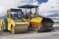 Asphalt paving machine and heavy vibratory roller close-up. A paver finisher, asphalt finisher or paving machine placing a layer Royalty Free Stock Photo