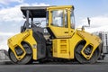 Asphalt paving machine and heavy vibratory roller close-up. A paver finisher, asphalt finisher or paving machine placing a layer Royalty Free Stock Photo