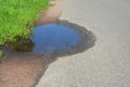 Asphalt on puddles. Pot hole or pothole image of a broken cracked asphalt pavement. Royalty Free Stock Photo