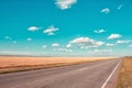 Asphalt road, blue sky with beautiful clouds and golden wheat field. Rural landscape. Royalty Free Stock Photo